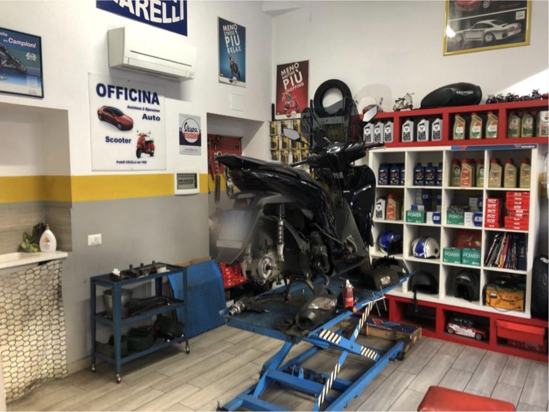 Uno scooter smontato sul ponte di sollevamento nell'officina Fratelli Colella, con la targa sfocata