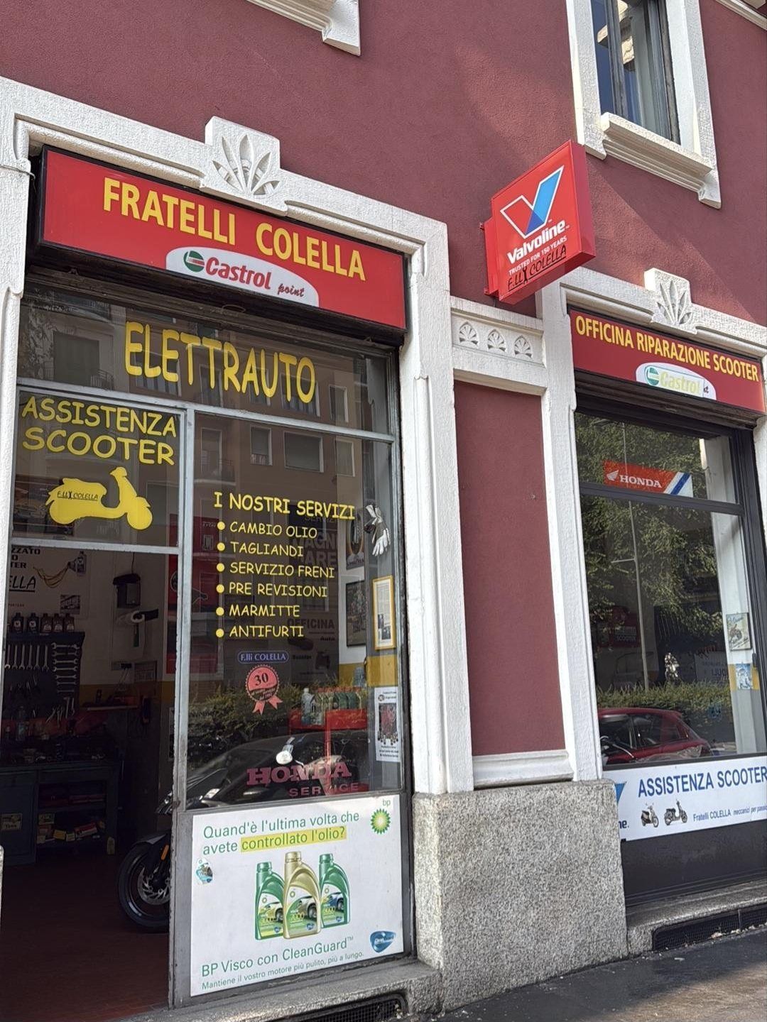 La vetrina rossa e gialla dell'officina Fratelli Colella in Viale Gian Galeazzo 6 a Milano, con le insegne Elettrauto e Assistenza Scooter